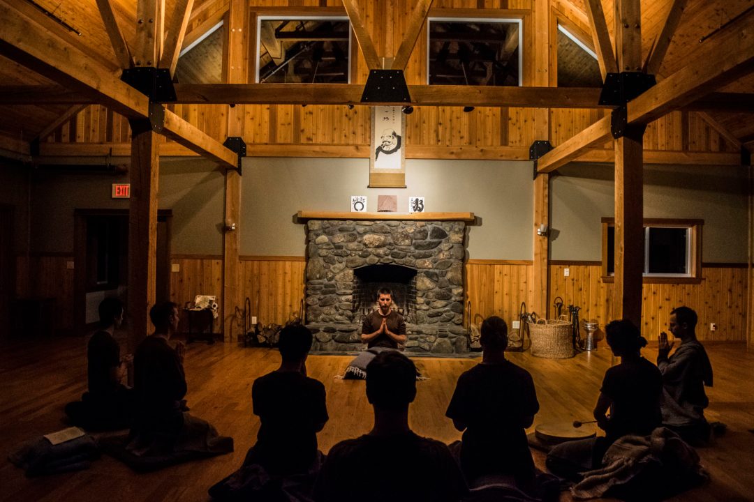 Residents sitting in meditation together by the fire in the main hall
